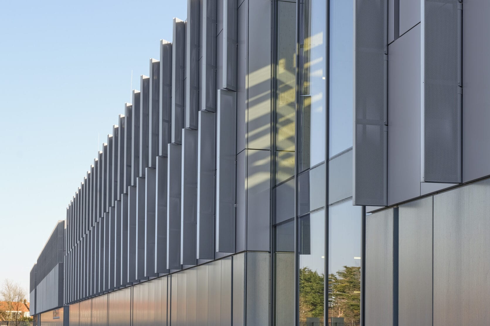 Metadecor | MD Flack (plint en luifel), MD Lamel en MD Designperforatie (bovenkant) | DV&O in Zaanstad DV&O in Zaanstad. Door het spel van zonlicht en schaduw op de geperforeerde lamellen verandert de uitstraling van het gebouw gedurende de dag.