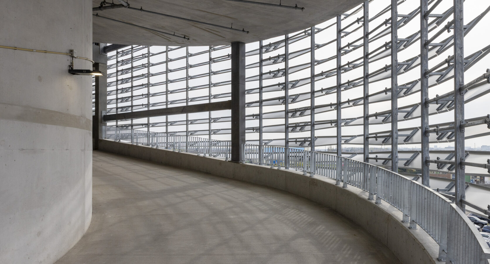 Aluminium lamellengevel aan de binnenzijde van parkeergarage P30 Zaventem De aluminium lamellengevel aan de binnenzijde van parkeergarage P30 op Brussels Airport, met gebogen gevel en open draagconstructie.